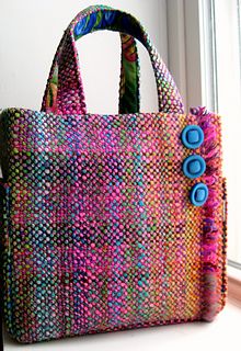 a multicolored bag sitting on top of a window sill next to a vase