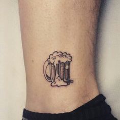 a small tattoo on the ankle of a man with a mug of beer in it