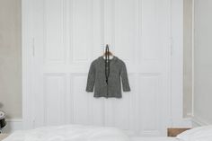 a coat hanging on the wall in a room with white closets and bedding