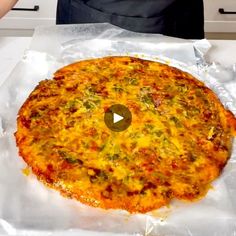 a pizza sitting on top of aluminum foil covered in cheese and toppings, being held by a person