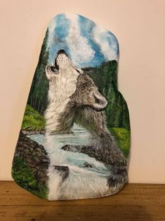 a painted rock sitting on top of a wooden table next to a white and black bear