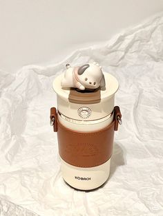 a white and brown container with a cat on top