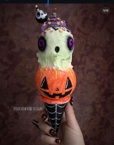 a hand holding an ice cream cone decorated with halloween decorations