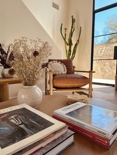 a living room filled with lots of furniture and books on top of a wooden table