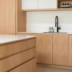 a kitchen with wooden cabinets and white counter tops, along with a black faucet