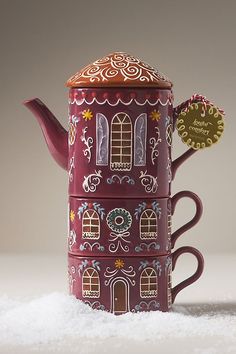 a red teapot sitting on top of a pile of snow