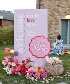 a welcome sign is surrounded by flowers and other decorations in front of a brick building