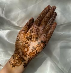 a woman's hand with hennap on it and white fabric in the background