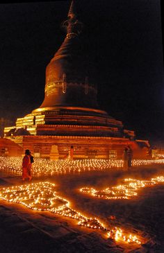 people standing in front of a large building with lots of lit candles on the ground