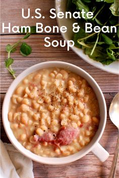 a white bowl filled with beans and meat next to a plate of spinach leaves