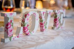 the word love spelled with flowers sits on a table next to wine glasses and plates