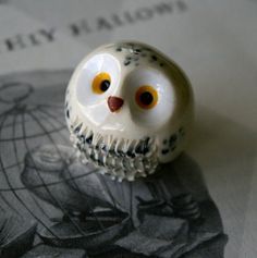 an owl figurine sitting on top of a piece of paper with yellow eyes