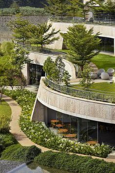 an aerial view of a circular building surrounded by greenery and trees on the hillside