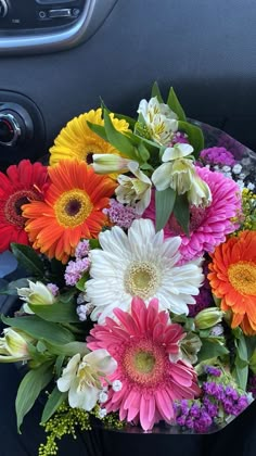 a bouquet of colorful flowers sitting in the center of a car