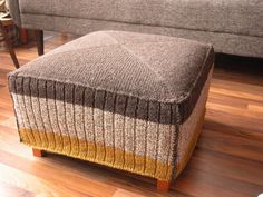 a footstool sitting on top of a wooden floor next to a gray couch