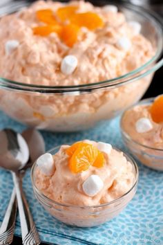 two bowls filled with orange and marshmallows on top of a blue table cloth