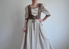 Vintage beige and brown linen folk dress, from the 1990s era Women's linen peasant dress with a long flare skirt  with 2 hand pockets, short puffy sleeves and brown laced corset upper part. Closes at the back with silver metal buttons which are also used on the cuffs of the sleeves Size - marked 38 DE which is 8 US.  Model is 171 cm tall, wears 38 EU, cup size A or 8 US, dress fits big in the bust area and shoulders! For a fitted look will be more suitable for size 40 EU or 38 EU with a large bu Fitted Beige Peasant Dress, Beige Fitted Peasant Dress, Fitted Brown Cottagecore Dress, Long Flare Skirt, Brown Corset, Folk Dress, Dirndl Dress, Folk Dresses, Dress Beige