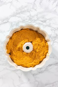 an overhead view of a cake in a pan on a marble counter top with a white candle