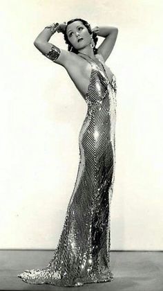 an old photo of a woman in a long dress with her hands on her head