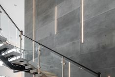 an indoor stair case with glass handrails and lights on the wall next to it