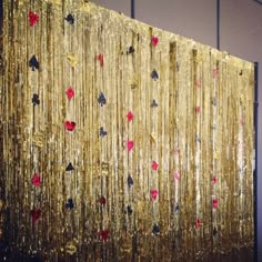 a gold curtain with red and black hearts hanging from it's side in front of a wall