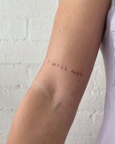 a woman's arm with the word will not written on it in cursive font