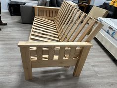 a wooden bed frame sitting on top of a hard wood floor next to a couch