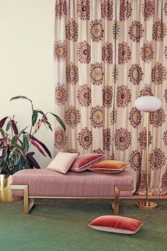 a living room with a pink couch and floor lamp next to the curtained window