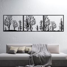 three black and white paintings on the wall above a couch in a modern living room