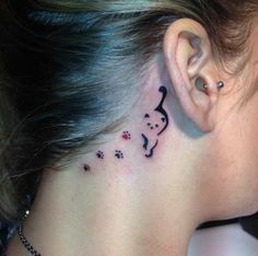 a woman's behind the ear has a cat and dog tattoo on her left side