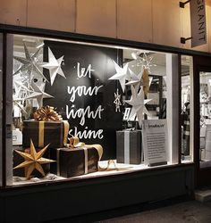 a store front with christmas decorations and presents in it's display window at night