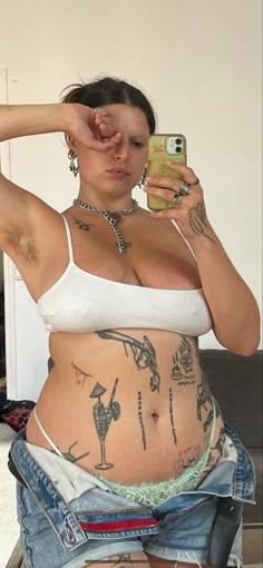 a woman with tattoos on her stomach taking a selfie