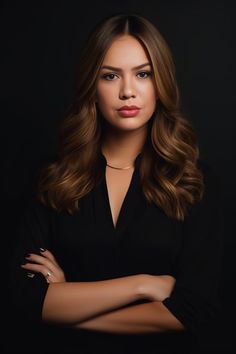 a woman with her arms crossed posing for a photo in front of a black background