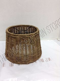 an empty wicker basket sitting on top of a white sheet with the lid down