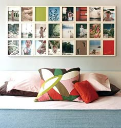 a white bed topped with lots of pillows and pictures on the wall above it's headboard