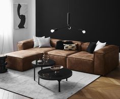 a living room with black walls and brown couches, white rugs and coffee table