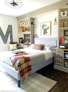 a bed room with a neatly made bed and lots of books on the shelves above it