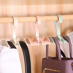 three purses hanging on a wooden rack next to a handbag and bag holder