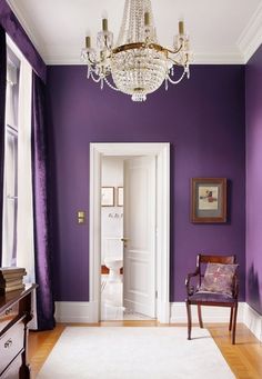 a room with purple walls and white carpeted flooring in the center is a chandelier