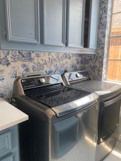 a washer and dryer in a kitchen with blue wallpaper on the walls