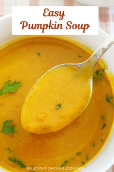 a spoon full of pumpkin soup in a white bowl with the words easy pumpkin soup above it