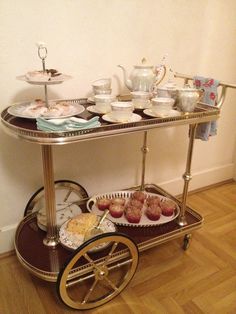 a gold serving cart filled with pastries on top of a hard wood floor