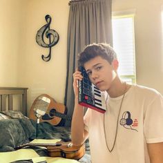 a young man holding up a cell phone to his ear