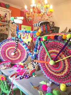 a table topped with lots of colorful items next to a chandelier hanging from the ceiling