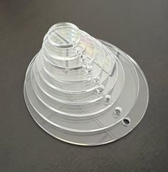 a stack of clear plastic plates sitting on top of a black table next to each other