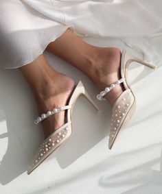 a woman's feet in high heels with pearls on the toes and white dress