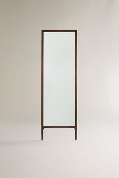 a tall mirror sitting on top of a white floor next to a wooden framed object