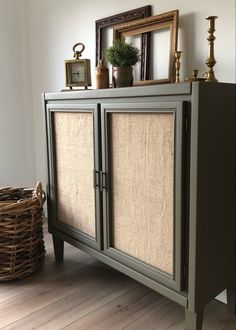 a gray cabinet with two doors and some pictures on top of it in a room