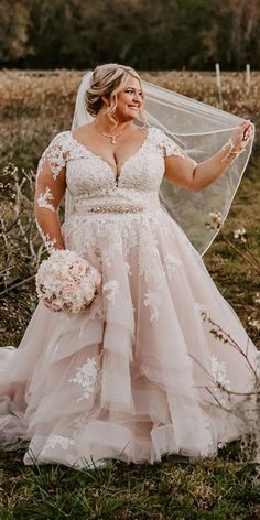 a woman in a wedding dress is holding a veil and posing for the camera outside