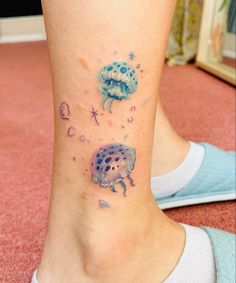 a woman's foot with tattoos on it and an image of jellyfishs